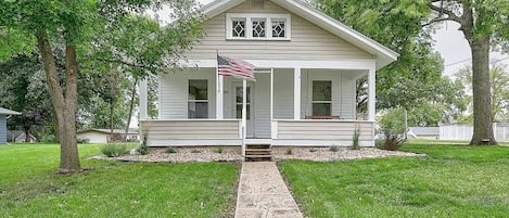 A single-story house with a front porch, a small front yard, and a pathway leading to the entrance.