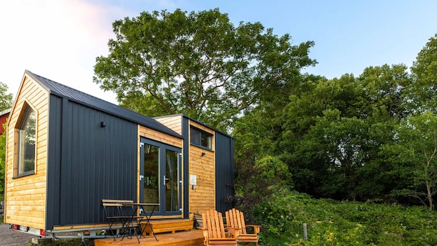 Une petite cabane avec une terrasse, une table et deux chaises.