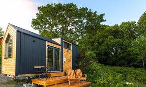 A small cabin with a deck, a table, and two chairs. - Kullaberg Tiny House by Tiny Away (Mölle)