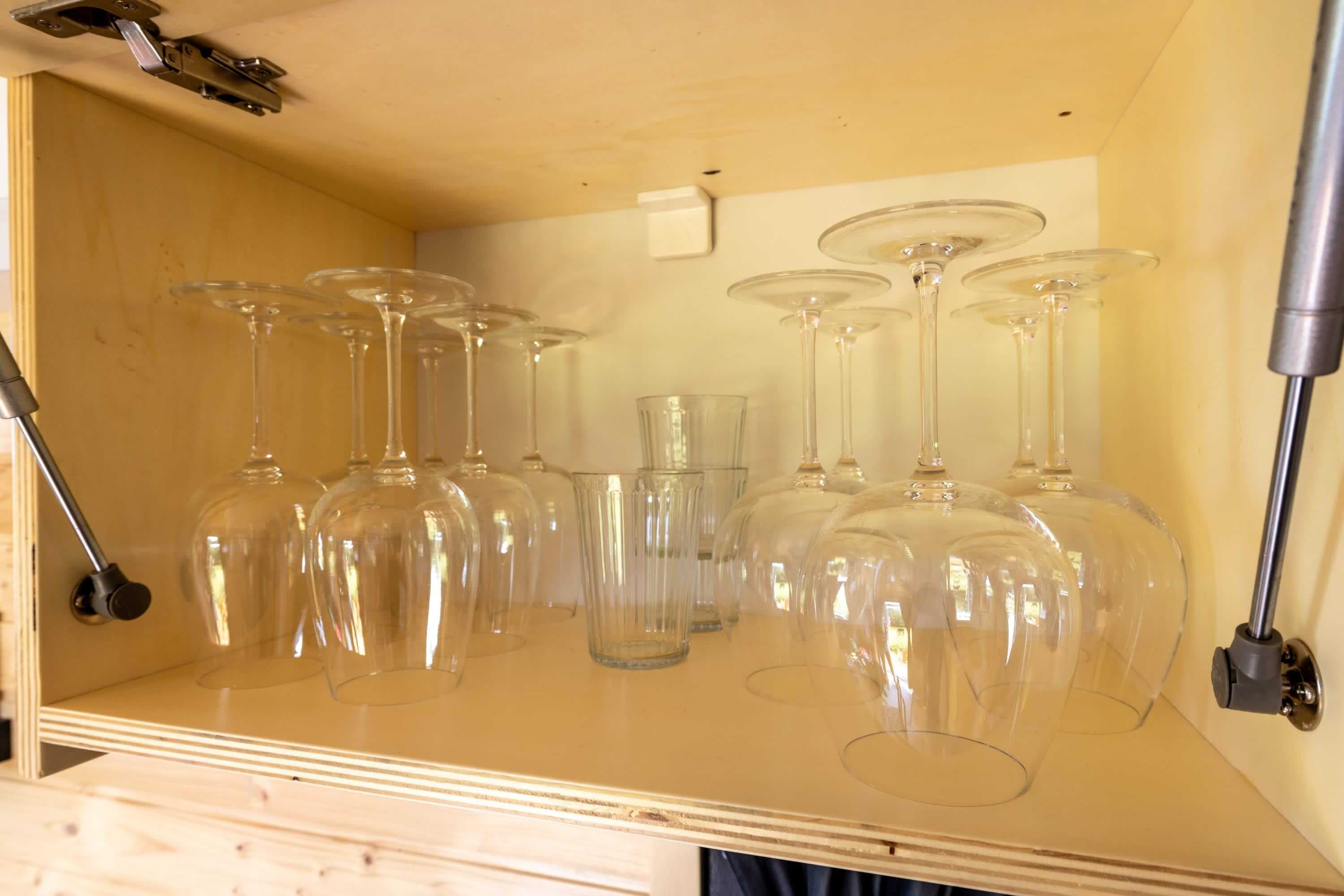 Een houten kast met verschillende wijnglazen en een wijnrek.