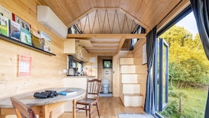 Un intérieur en bois comprenant un coin repas, une cuisine et une vue sur l’extérieur.