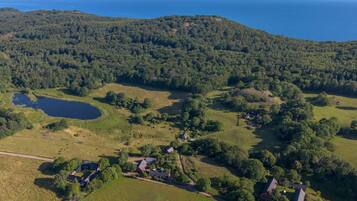 An aerial view of a rural area with a lake, scattered houses, and dense forest.