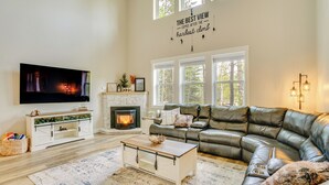 Un salón con chimenea, sofá de cuero y televisor.