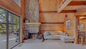 L'intérieur d'un chalet confortable, avec une cheminée en pierre, un canapé et un coin repas.