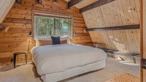 Une chambre confortable avec un grand lit, une fenêtre et un plafond en pente.