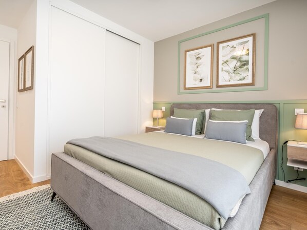 A neatly arranged bedroom with a bed, bedside tables, and framed artwork on the wall.