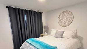 Un dormitorio con cama, una mesita de noche, una lámpara de pared y un elemento decorativo en la pared.