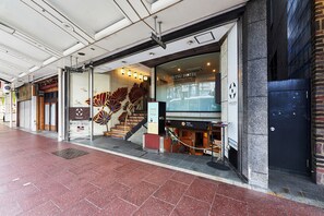 Het uiterlijk van Hotel Izutsu, met een zichtbare ingang, een trap die naar de ingang leidt, en een bord dat een voetverzorgingsdienst aangeeft.