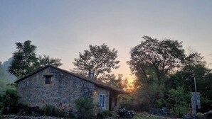 Una casa de piedra con un pequeño porche, rodeada de un jardín con un sendero de piedra.