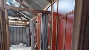 Una hilera de camas individuales con sábanas blancas, cabeceras de madera y cortinas.