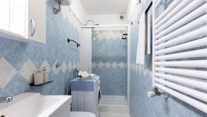 Une salle de bain équipée d’une douche, de toilettes, d’un lavabo et d’un porte-serviettes.
