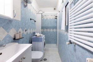 Ein Badezimmer mit Dusche, Toilette, Waschbecken und Handtuchhalter.