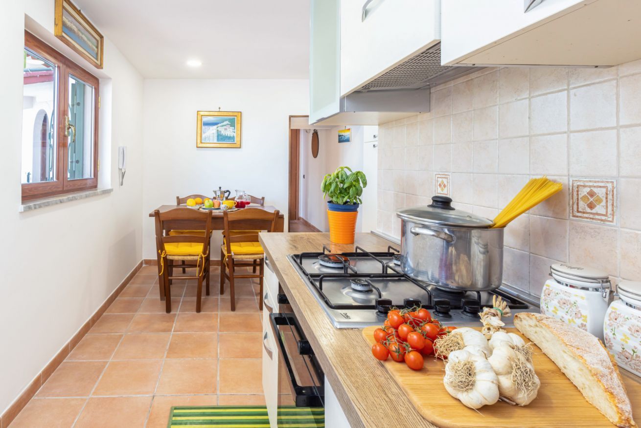 Une cuisine équipée d’une cuisinière, d’une table à manger avec des chaises, d’une fenêtre et d’une plante en pot.