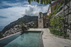 Une piscine avec vue sur un village côtier et les montagnes.