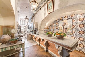 Una cucina con piano di lavoro in marmo, zoccolo in piastrelle e lampade a sospensione.