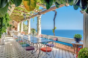A terrace with a table and chairs, overlooking the sea.
