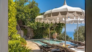 An outdoor swimming pool area with lounge chairs and a canopy. - MyExclusiveItaly - Lux Historic Villa with Pool & Amalfi Coast View (Positano)