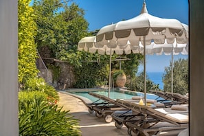Zona de piscina al aire libre con sillones de descanso y una pérgola.