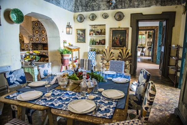 Comedor con una mesa dispuesta para cuatro personas, rodeado de paredes con diseños y varios objetos decorativos.