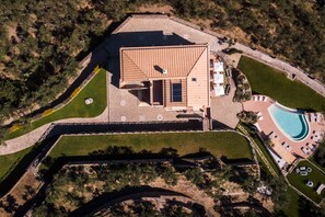 Vista aérea de una propiedad con un edificio grande, una piscina y zonas ajardinadas.