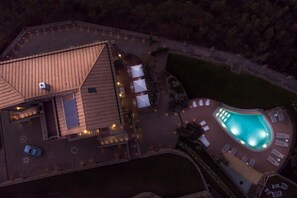 An aerial view of a hotel with a swimming pool, outdoor seating, and a well-lit patio area. - MyExclusiveItaly - Villa Breathtaking view near Nerano (Massa Lubrense)