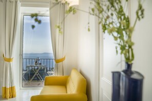 Un sofá amarillo en una habitación con vista al mar a través de un ventanal.