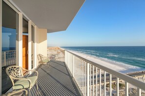Enjoy the ocean view from this balcony with a chair and table.