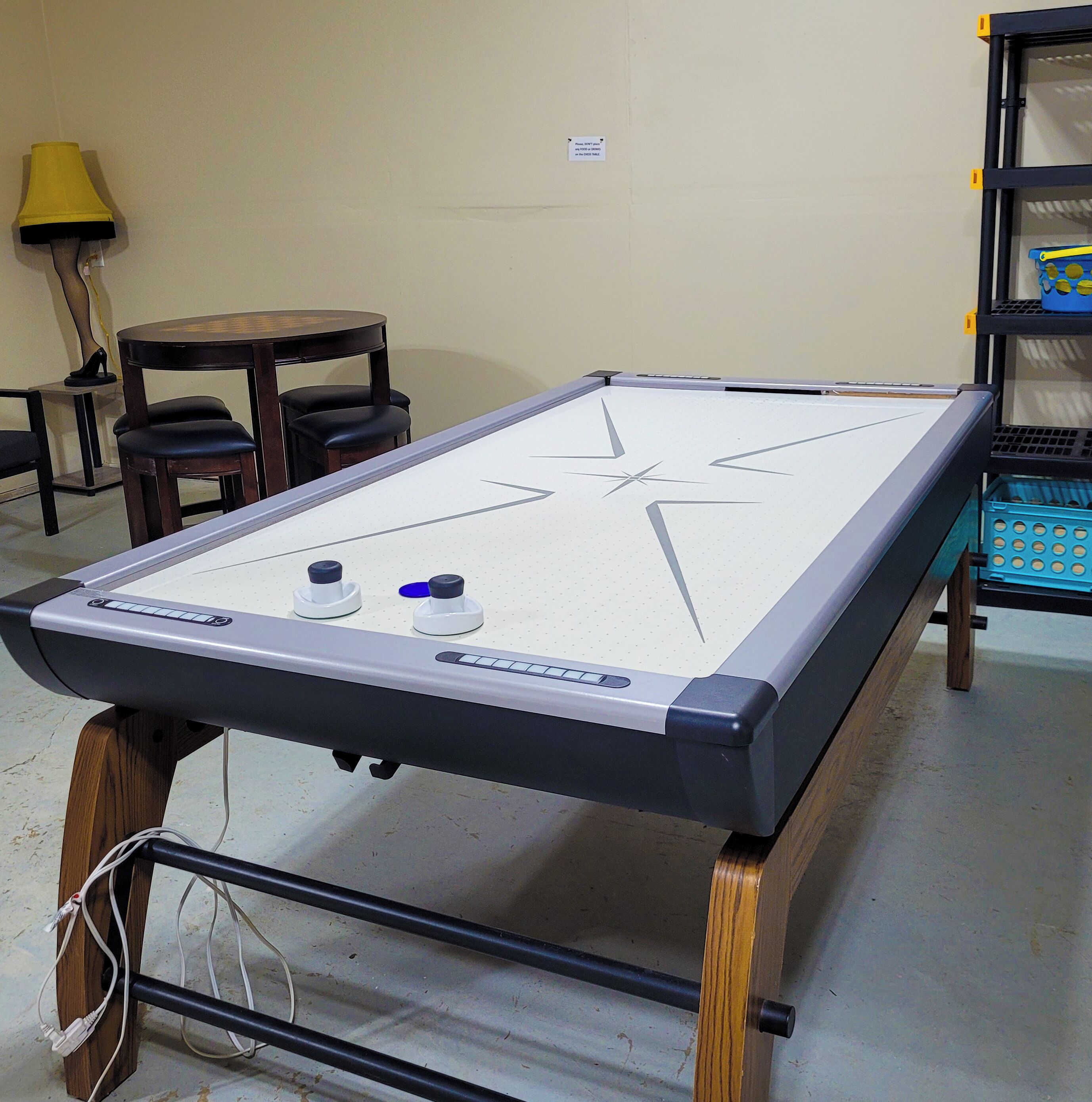 Une table de billard ornée d’un motif en étoile, entourée d’une table et de chaises en bois, et une lampe en arrière-plan.