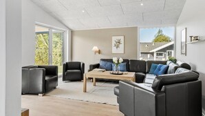 Een moderne woonkamer met een zithoek, een salontafel en een groot raam met uitzicht op het landschap.