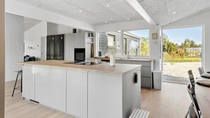 Een moderne keuken met een centraal eiland, inbouwapparatuur en grote ramen met uitzicht op de omgeving.