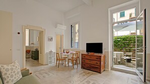A spacious living area with a sofa, a TV, a dining table with chairs, and a sliding glass door leading to an outdoor patio. - Beach & Relax - Private Parking and Veranda, Alassio, Italy (Alassio)