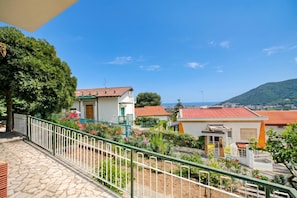 A residential area with a stone-paved pathway, a green metal railing, and houses with red-tiled roofs.
