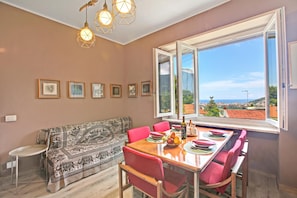 Un comedor con una mesa dispuesta para cuatro personas, un sofá y una ventana con vistas.