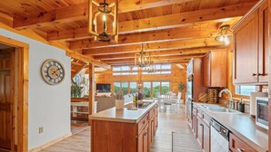 A spacious kitchen with wooden cabinets, a central island, and pendant lighting. - The perfect family retreat, hot tub, fire pit, playhouse for the kids with a zip line! Plenty of fun for the young and old alike! All while enjoying the majestic views of Juniata County. (Honey Grove)