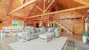 A spacious log cabin interior with a large living area, a dining area, and a kitchen. - The perfect family retreat, hot tub, fire pit, playhouse for the kids with a zip line! Plenty of fun for the young and old alike! All while enjoying the majestic views of Juniata County. (Honey Grove)