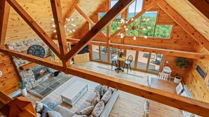 A spacious wooden cabin with a loft bedroom, a dining area, and a stone fireplace. - The perfect family retreat, hot tub, fire pit, playhouse for the kids with a zip line! Plenty of fun for the young and old alike! All while enjoying the majestic views of Juniata County. (Honey Grove)