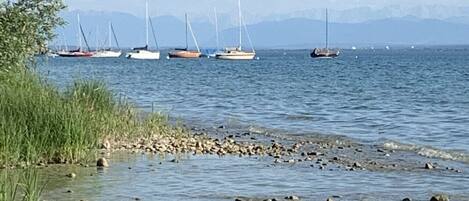 A calm lake with boats, clear skies, and distant mountains.