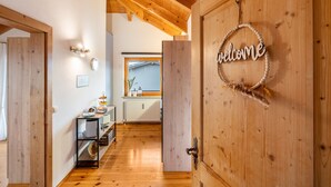 Un intérieur en bois avec une pancarte indiquant «Bienvenue», une porte en bois et une vue sur une autre pièce.