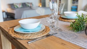 Une table à manger dressée avec un bol blanc, de la vaisselle transparente et un couteau.