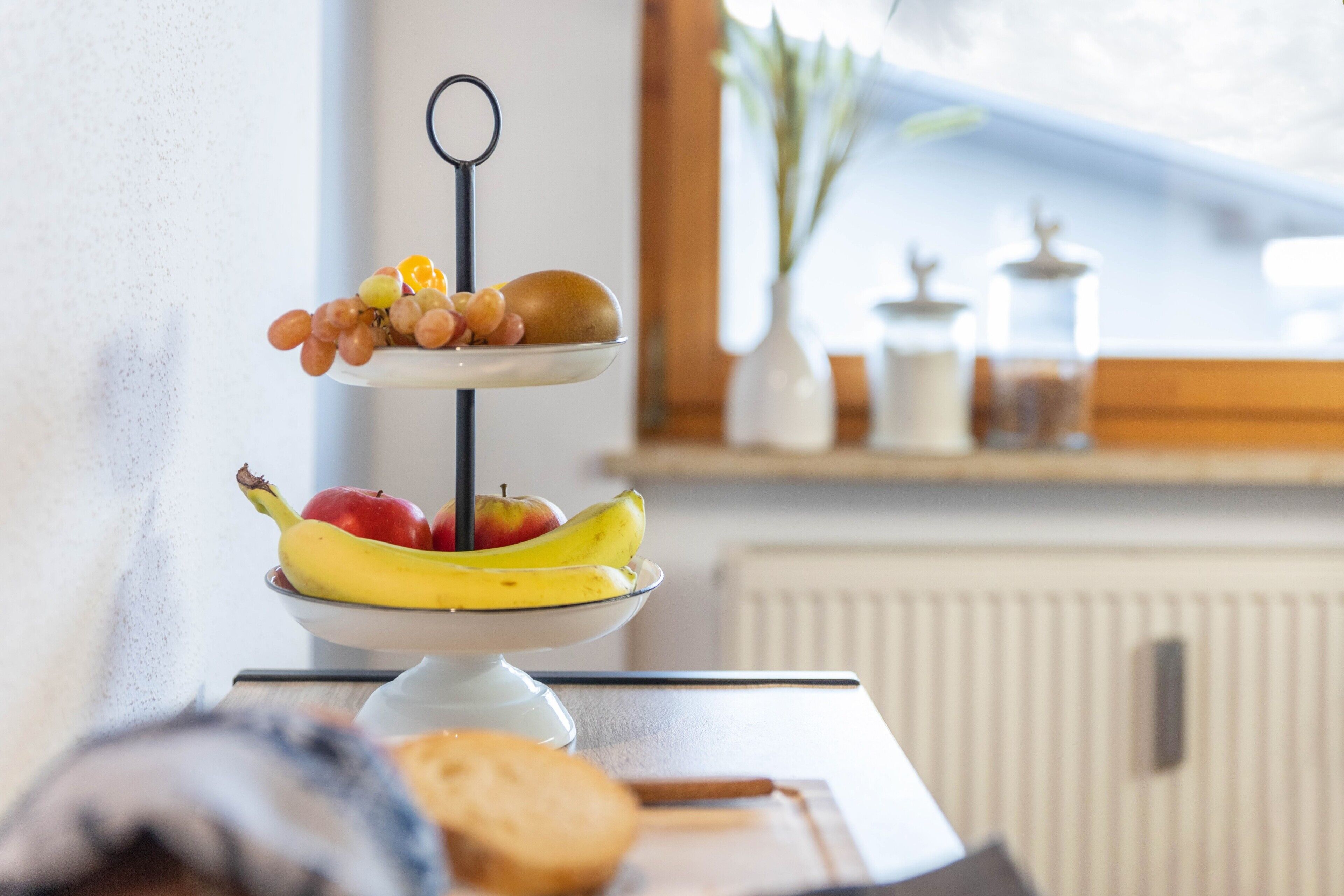 Ein mehrstufiger Obststand mit Bananen, Äpfeln und Trauben.
