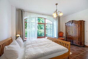 Une chambre à coucher avec un grand lit, une armoire en bois et une fenêtre avec des rideaux.