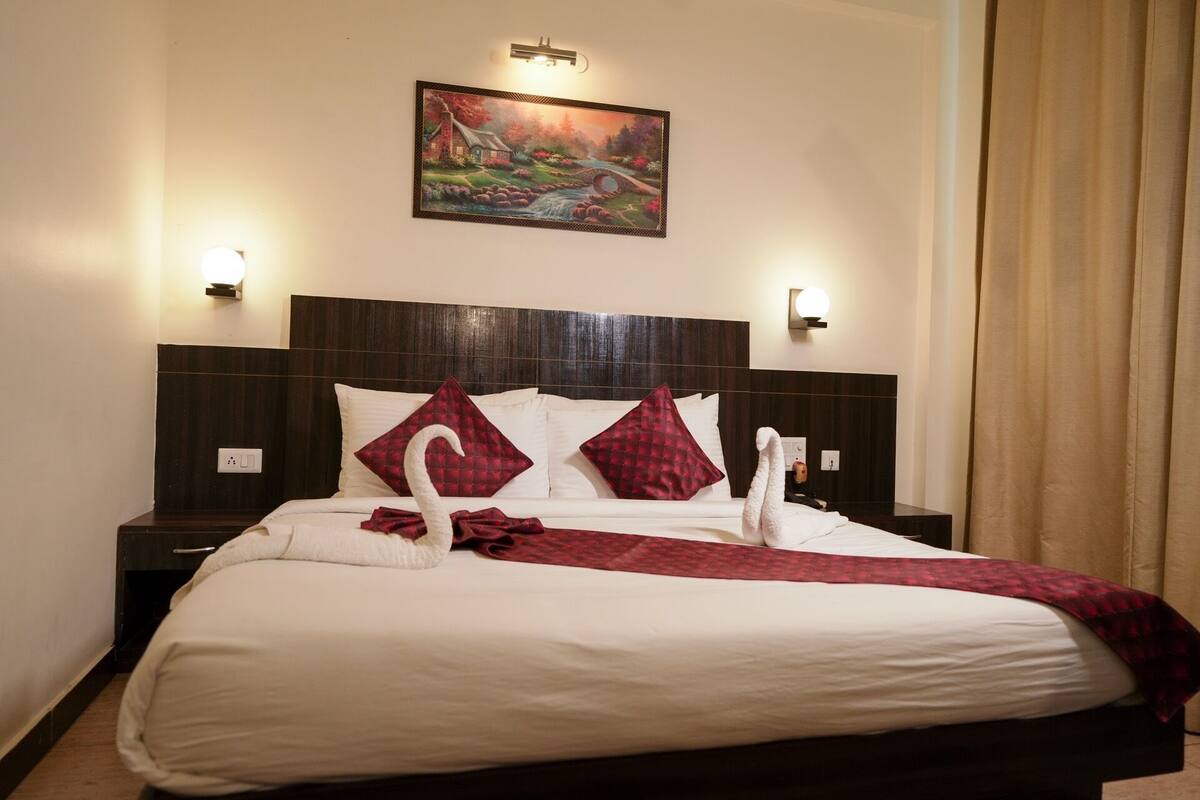 A neatly made bed with a red and white checkered blanket, two pillows, and a white towel folded on the bed.