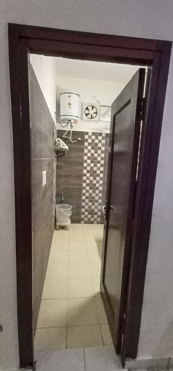 Un pasillo estrecho que conduce a un baño con un inodoro, un perchero y un calentador de agua.