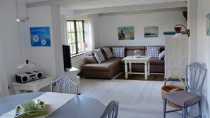 Un salon avec un canapé, une table, des chaises, un téléviseur et des œuvres d’art accrochées aux murs.