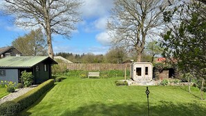 Un jardin bien entretenu, avec une pelouse, un banc en bois et un petit abri de jardin.