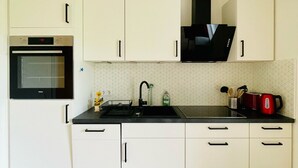 Una cocina moderna con armarios blancos, una estufa negra y una campana extractora negra.