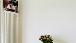 Un comedor con una mesa de madera, dos sillas, un florero con flores, una vela y un cartel en la pared.