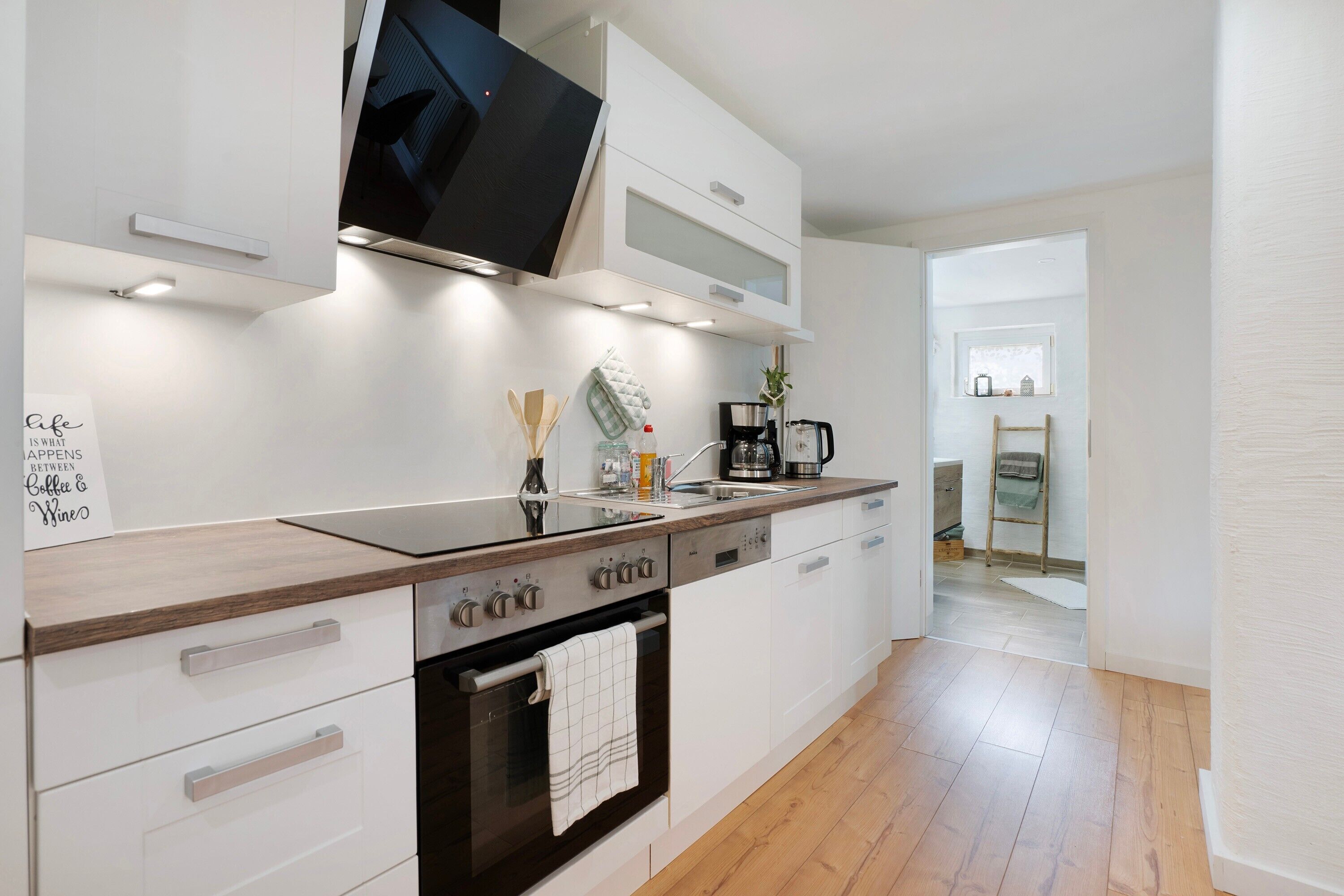 Een moderne keuken met een flatscreen-tv, een inbouwoven en witte kastjes.