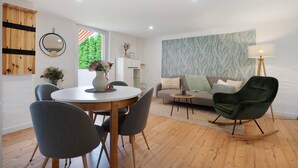 A modern living room with a dining table, chairs, a sofa, and a rocking chair. - Apartment 'Grünzweig' with Private Terrace by the Water (Oelsnitz/Vogtl.)