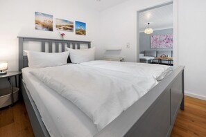 A modern bedroom with a bed, bedside table, lamp, and artwork on the wall.